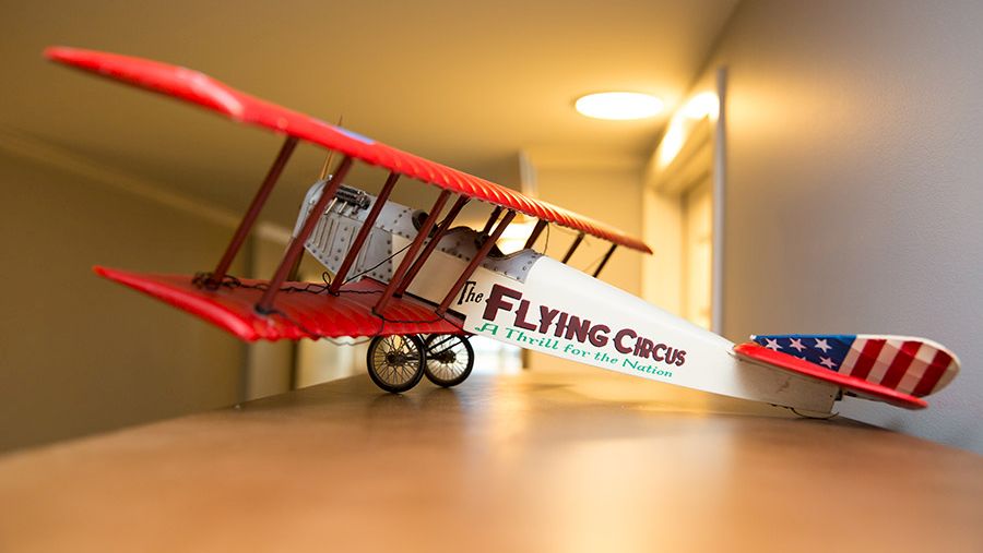 A model of a biplane with a red and white color scheme and "FLYING CIRCUS" written on the side, displayed indoors on a table.