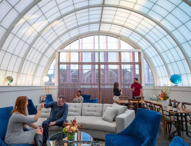 People socializing in a stylish lounge with arched ceiling and global decor, featuring comfortable seating and ambient lighting.