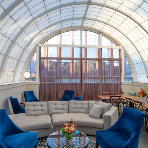 A stylish rooftop with blue and white chairs, and a decorative flowers display.