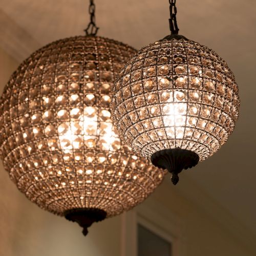 The image shows two spherical hanging chandeliers with intricate crystal designs, illuminating a room with a warm, soft light.