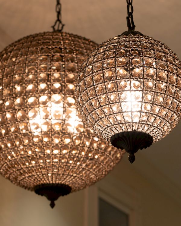 The image shows two spherical hanging chandeliers with intricate crystal designs, illuminating a room with a warm, soft light.