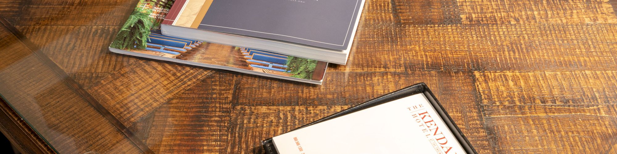 The image shows a wooden table with a stack of books, a notepad titled 