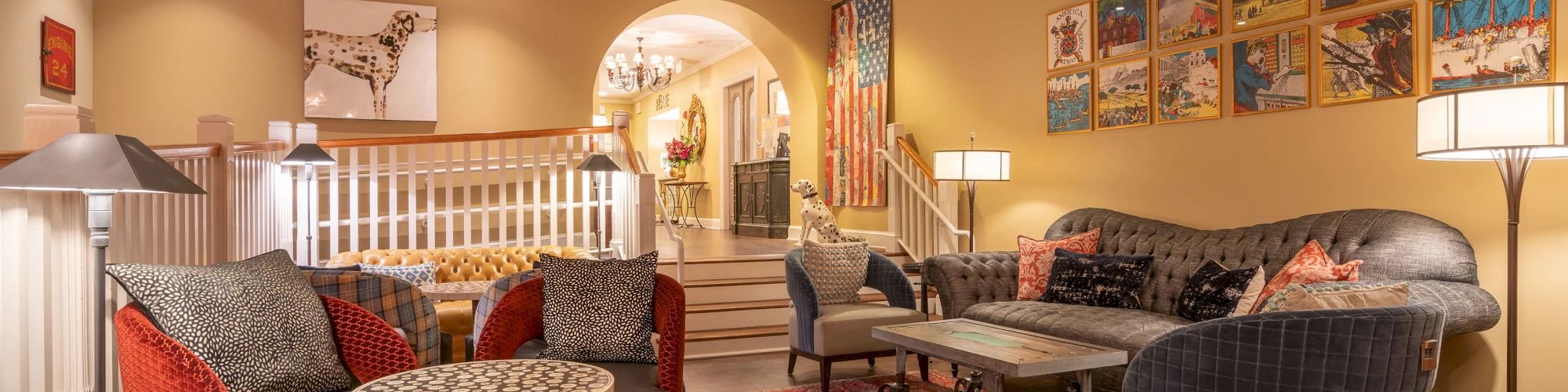 A cozy living room with elegant furniture, a colorful rug, wall art, and ambient lighting decorates the space warmly.