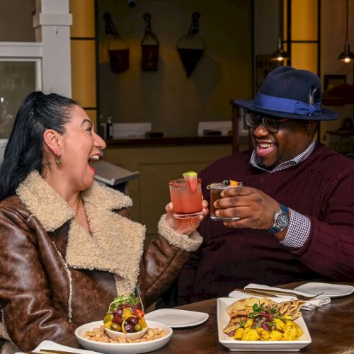 Three people share a meal at a table, with plates of food and drinks, indoors. Top it at 140 characters, always ending the sentence.